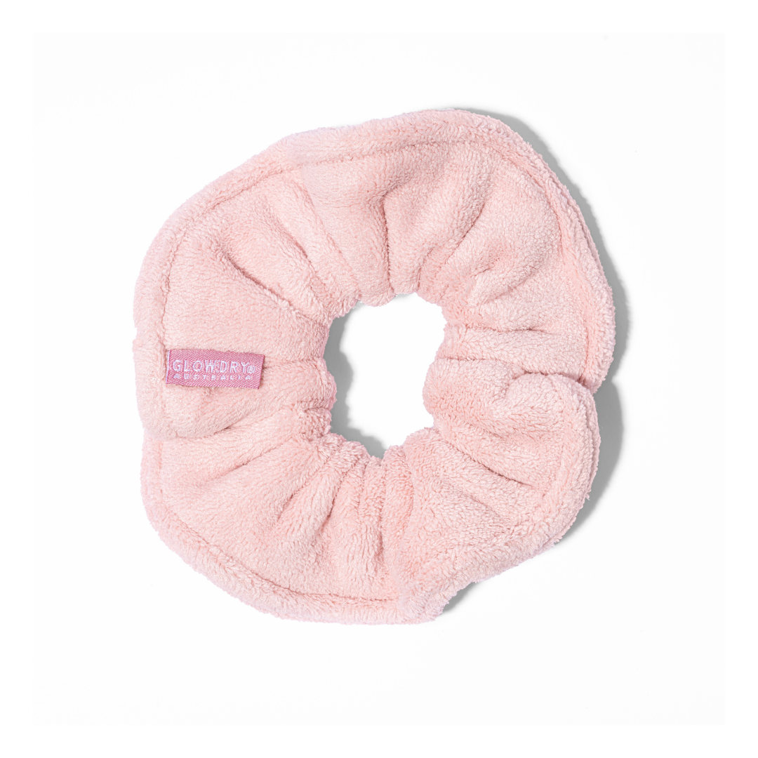 Pink soft terry towel luxe scrunchie in models tan with self tanner and manicured nails to pink backdrop