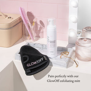 lifestyle picture of tan eraser mousse with exfoliating mitt in pink bathroom