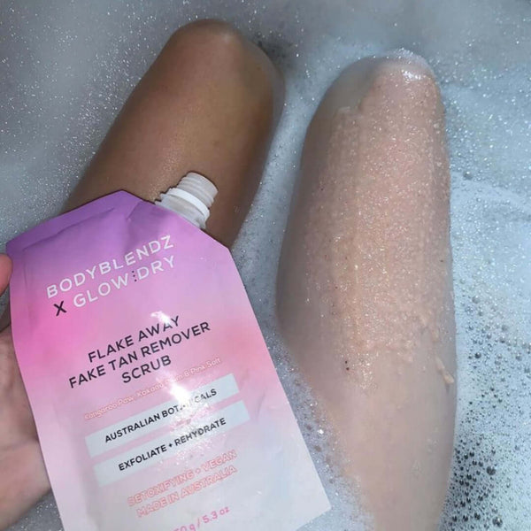 Flake Away Fake Tan Remover Scrub being used on a leg with visible foam.