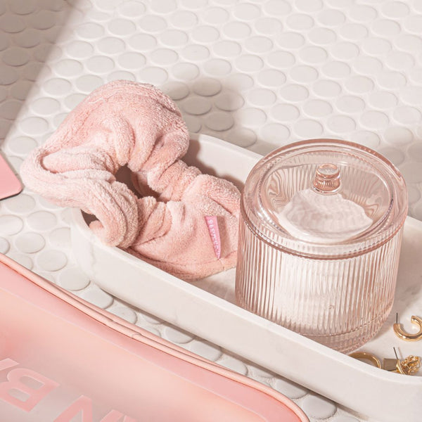 glowdry pink terry towel scrunchie flatlay picture beside bag on a vanit